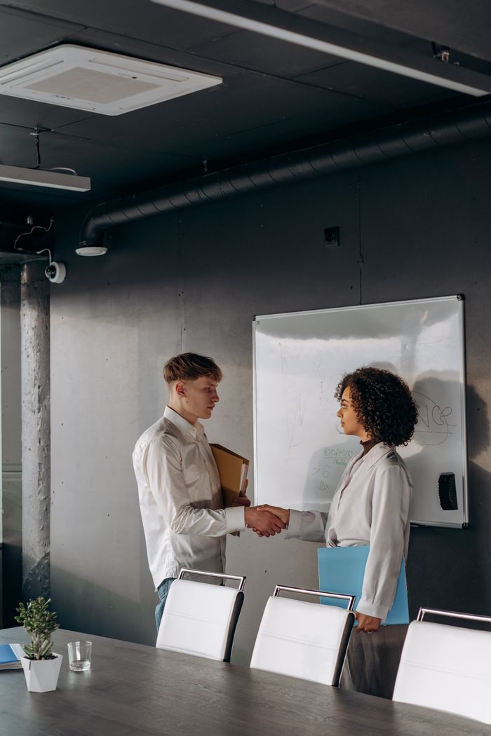 Two professionals shaking hands in a modern office setting global talent finder